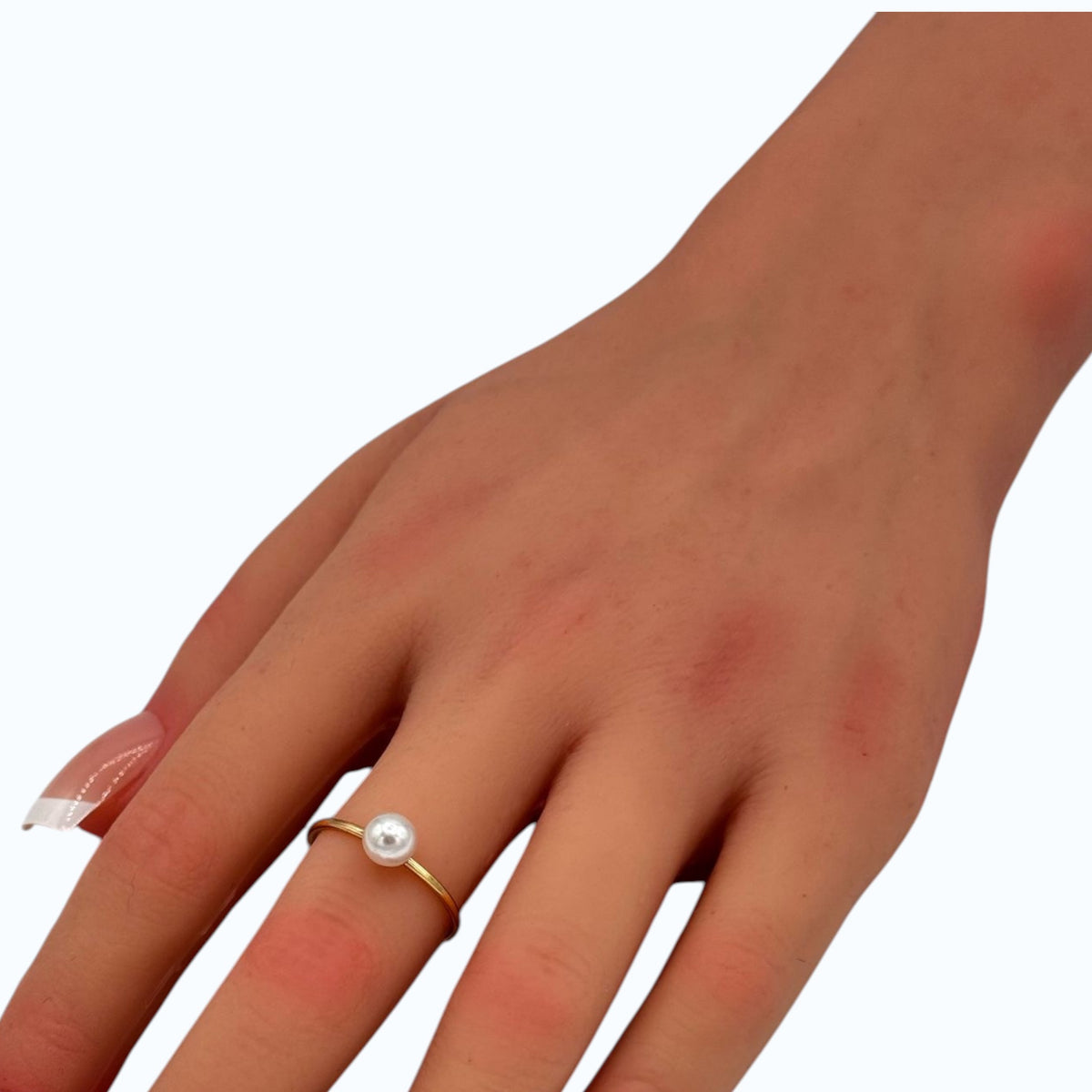 Gold-tone band ring with delicate faux pearl bead detail worn on a woman's finger.
