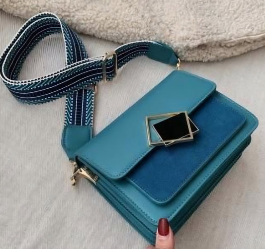 A blue Dorole Bayita crossbody bag with a striped strap and metallic hardware, displayed on a white surface.