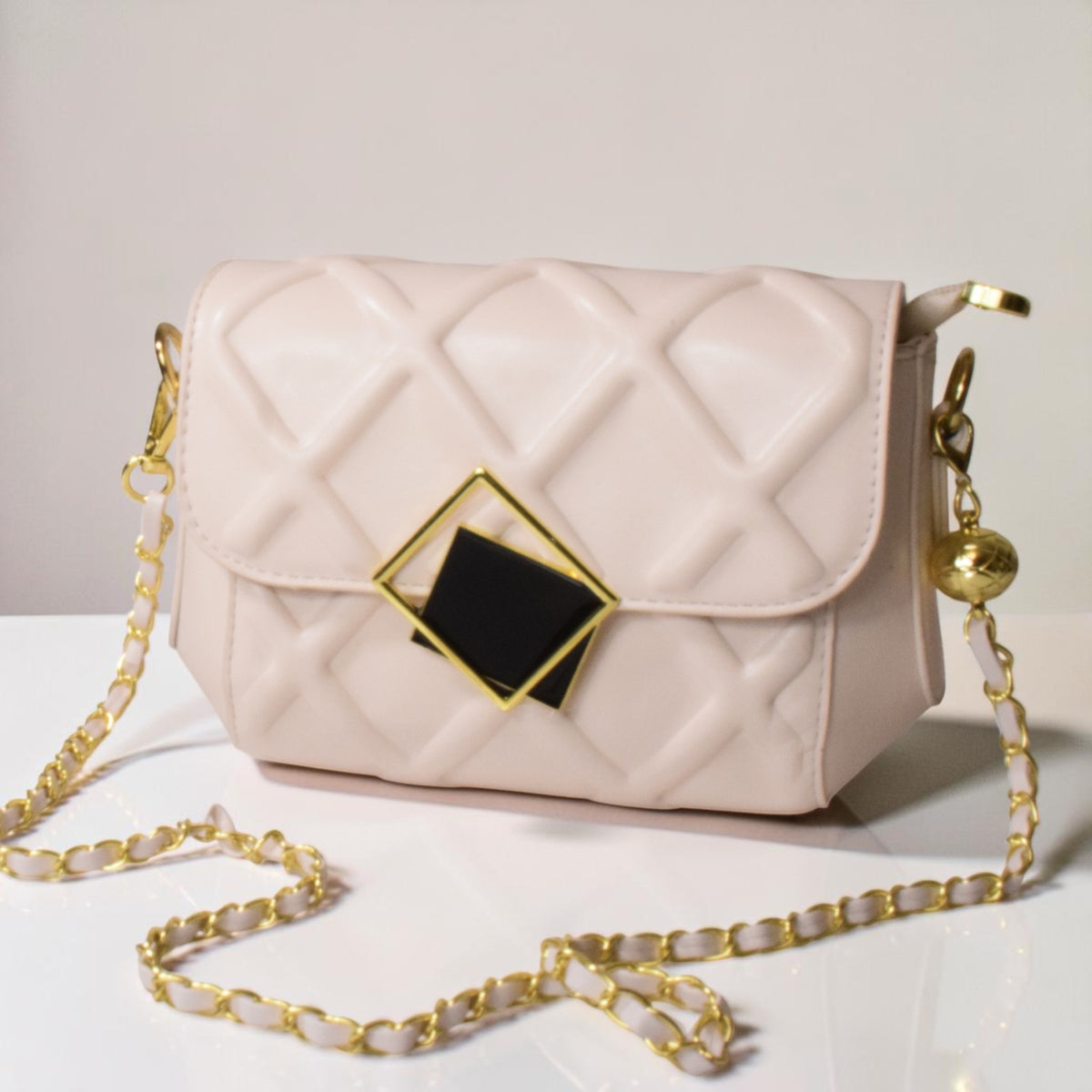 Off-white quilted crossbody handbag with a woven gold chain strap and metallic closure.