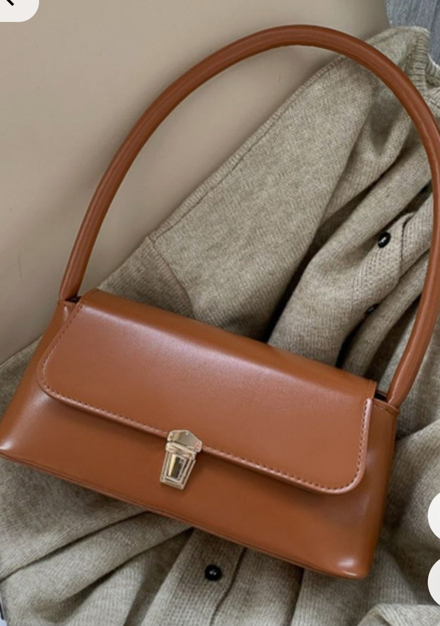 Brown leather handbag on a textured fabric background