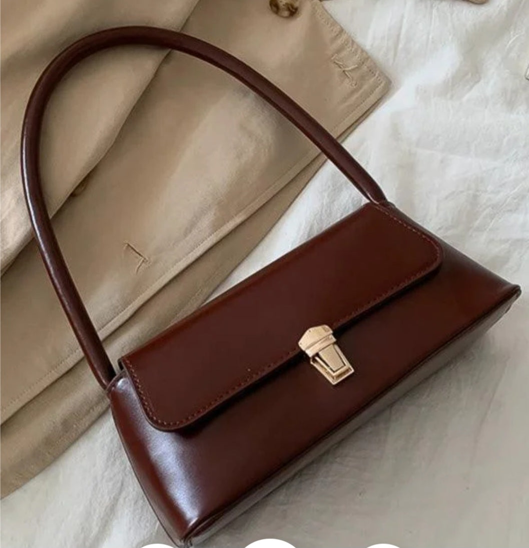 Brown handbag with a gold clasp on a light background