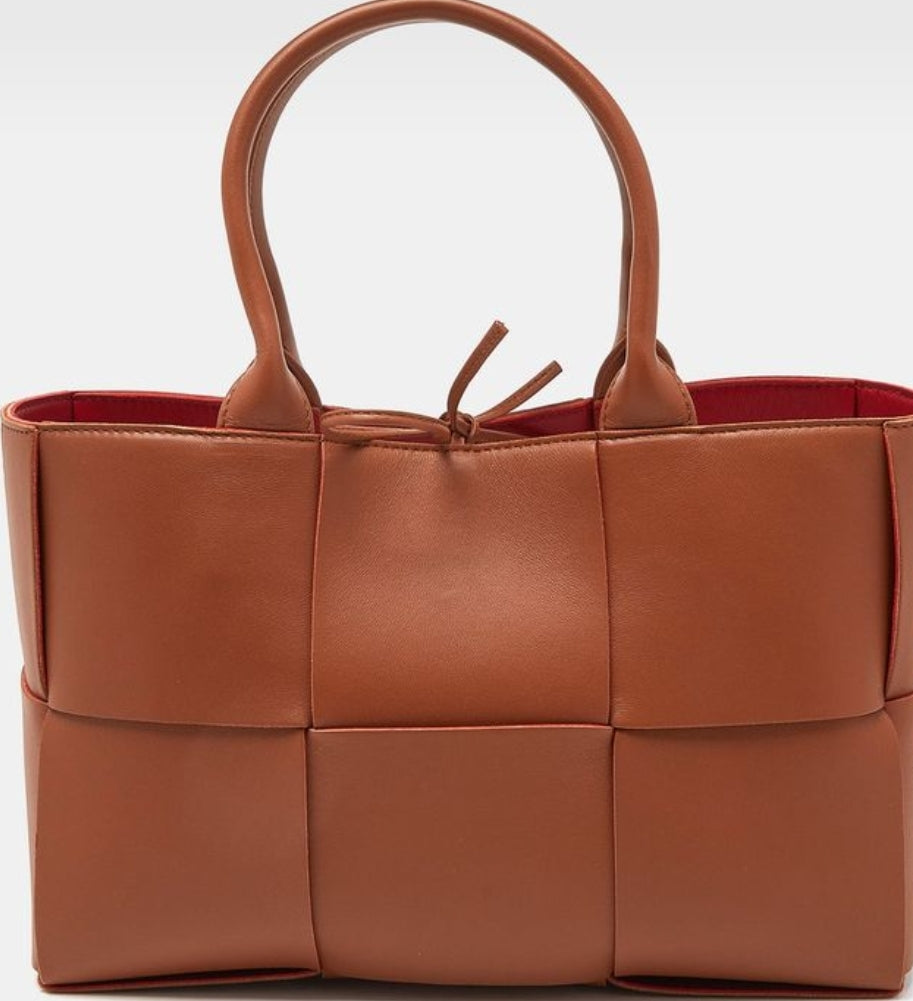 Brown leather handbag with woven design on a white background