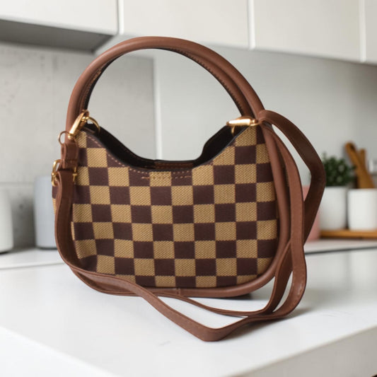 Brown and beige checkered handbag on a white surface with a kitchen background