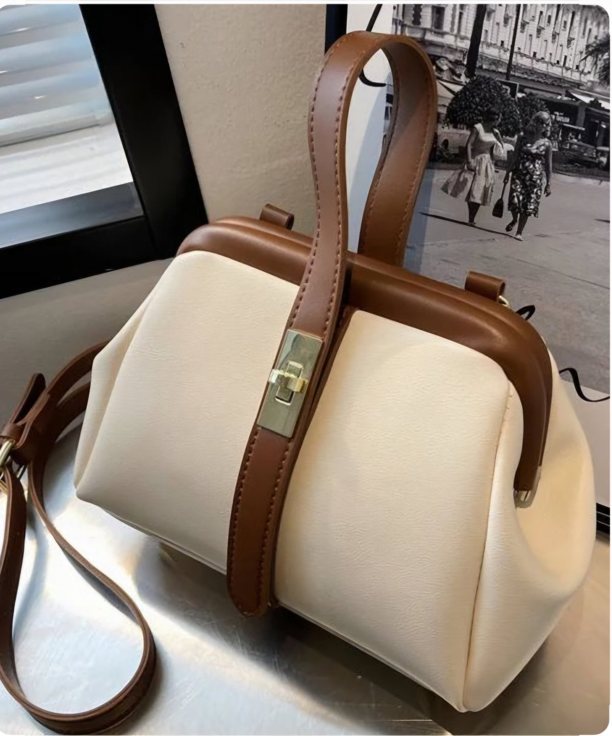 A beige and brown Dorole crossbody bag with a strap and metallic clasp, displayed in front of a blurred background.