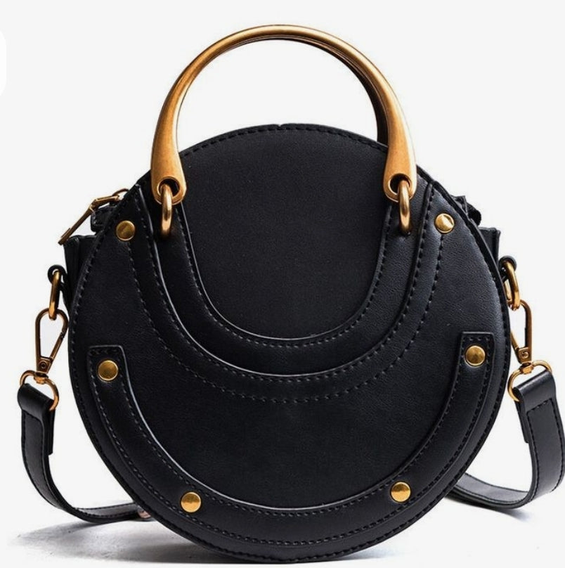 A black round crossbody bag with gold-colored hardware and a shoulder strap.