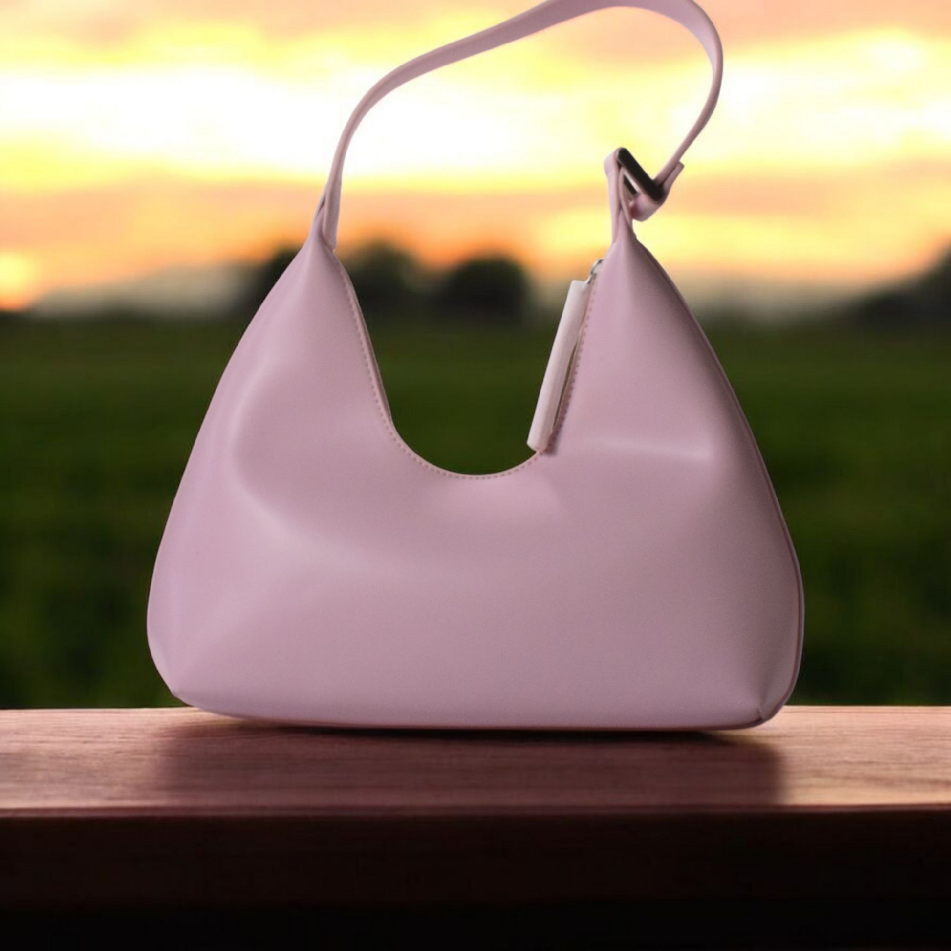 Soft pink curved shoulder bag with a chic top handle strap.