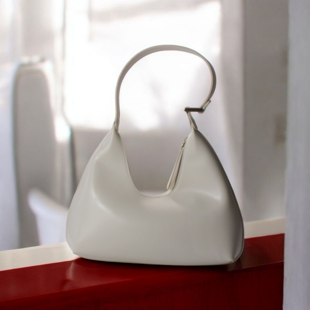 White handbag on a red surface with a blurred background