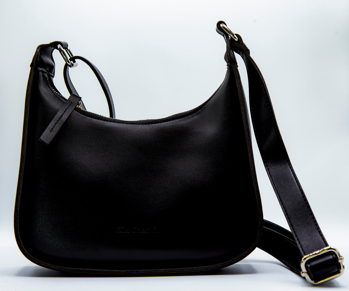 Black handbag with a strap on a light gray background