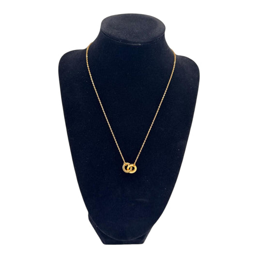 Gold necklace with interlocking rings on a black velvet stand against a white background